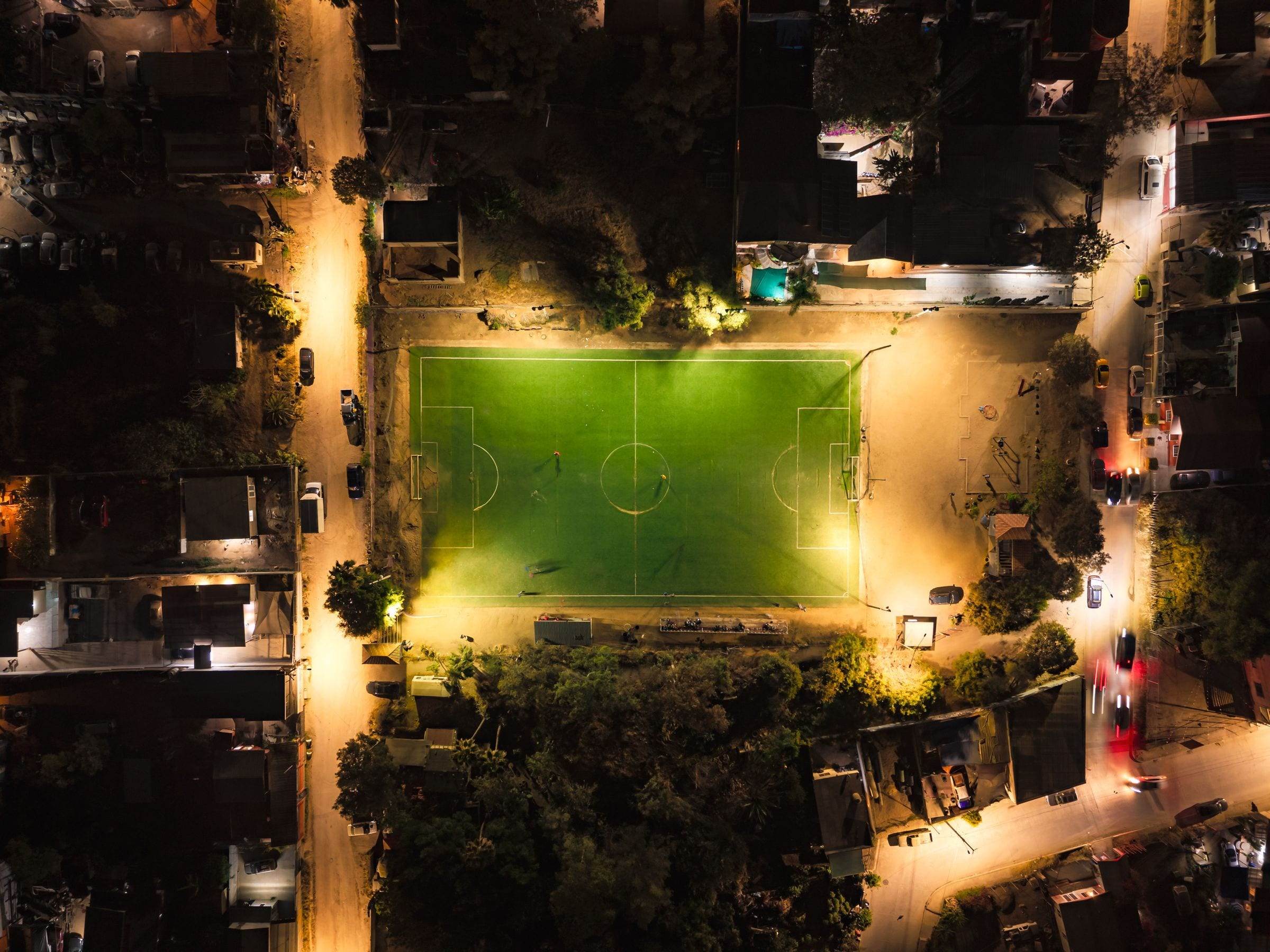Vue aérienne de nuit d’un terrain de football éclairé au milieu d’une ville