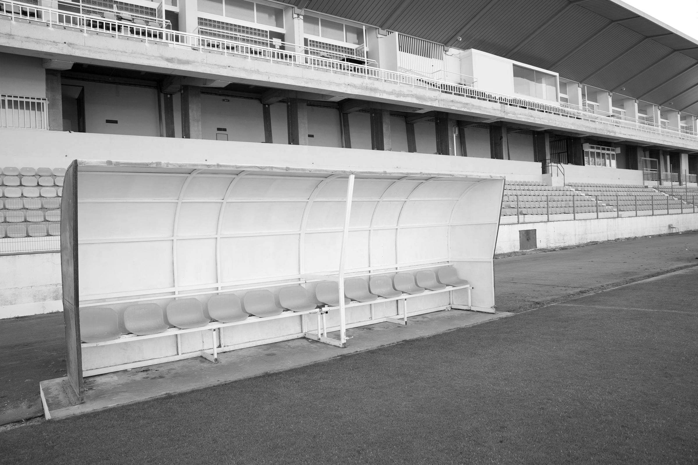Empty dugout beside the pitch, with a stand in the background