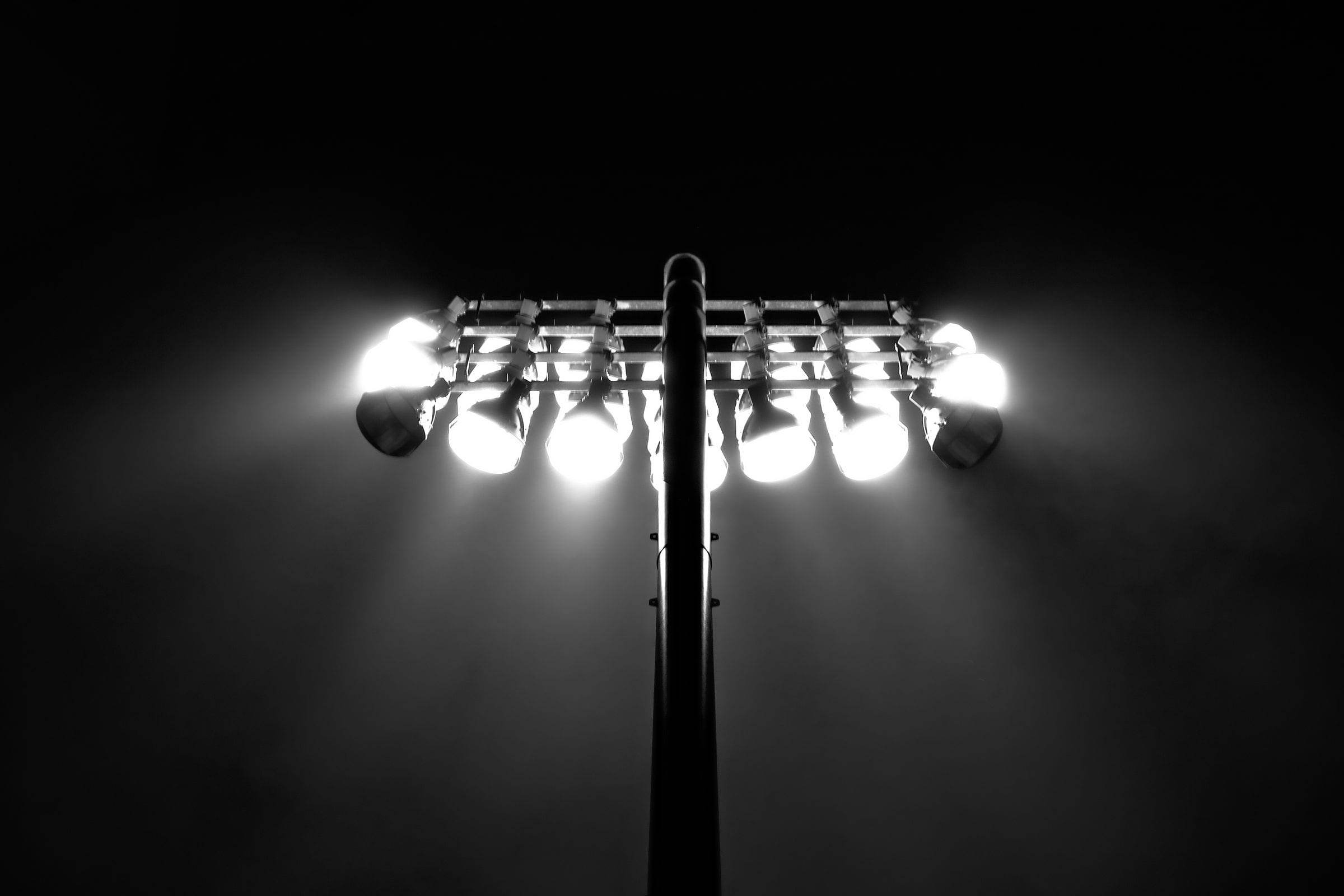 Projecteur de stade allumé dans la nuit, en noir et blanc