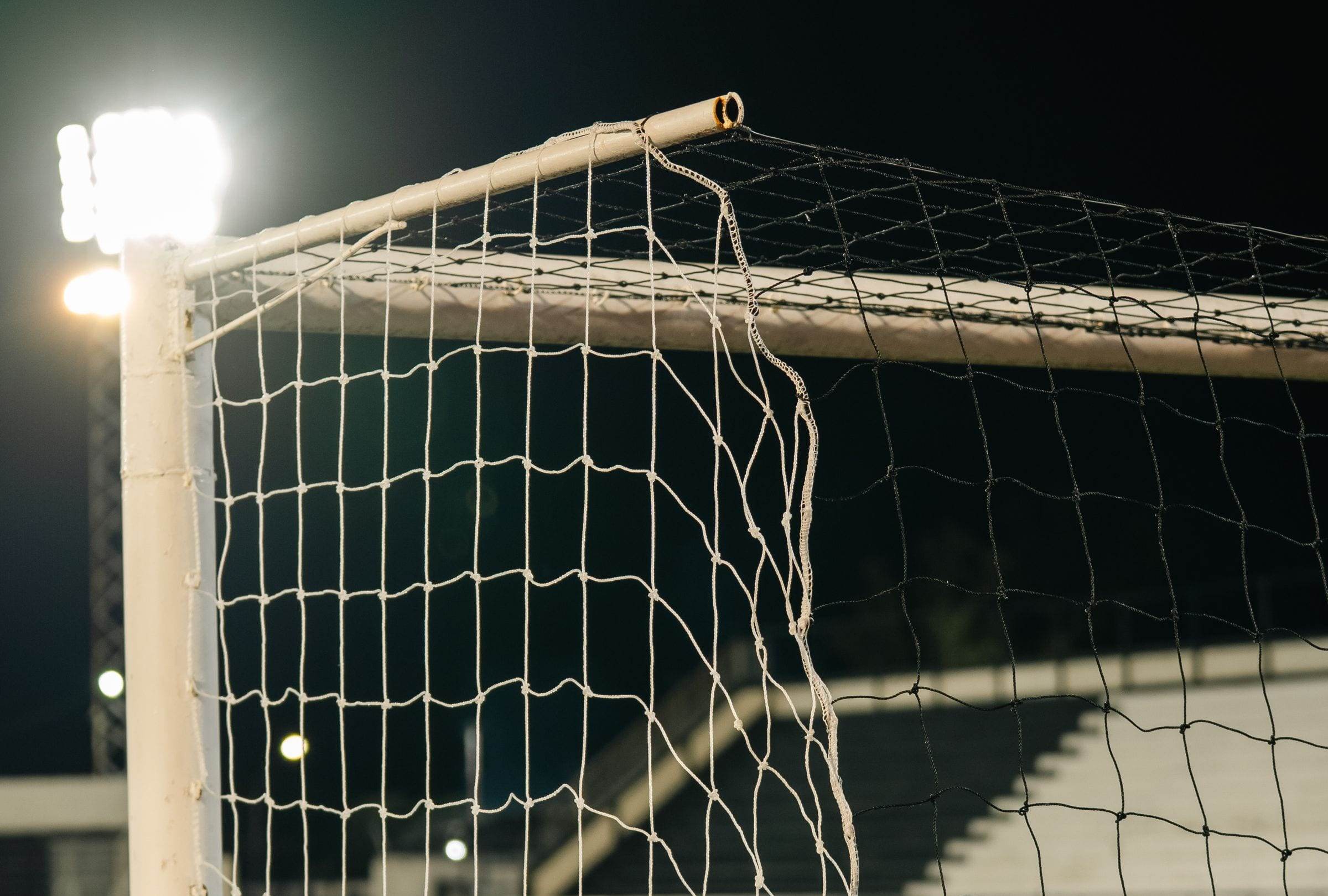Montant de but et filet sous un projecteur, de nuit