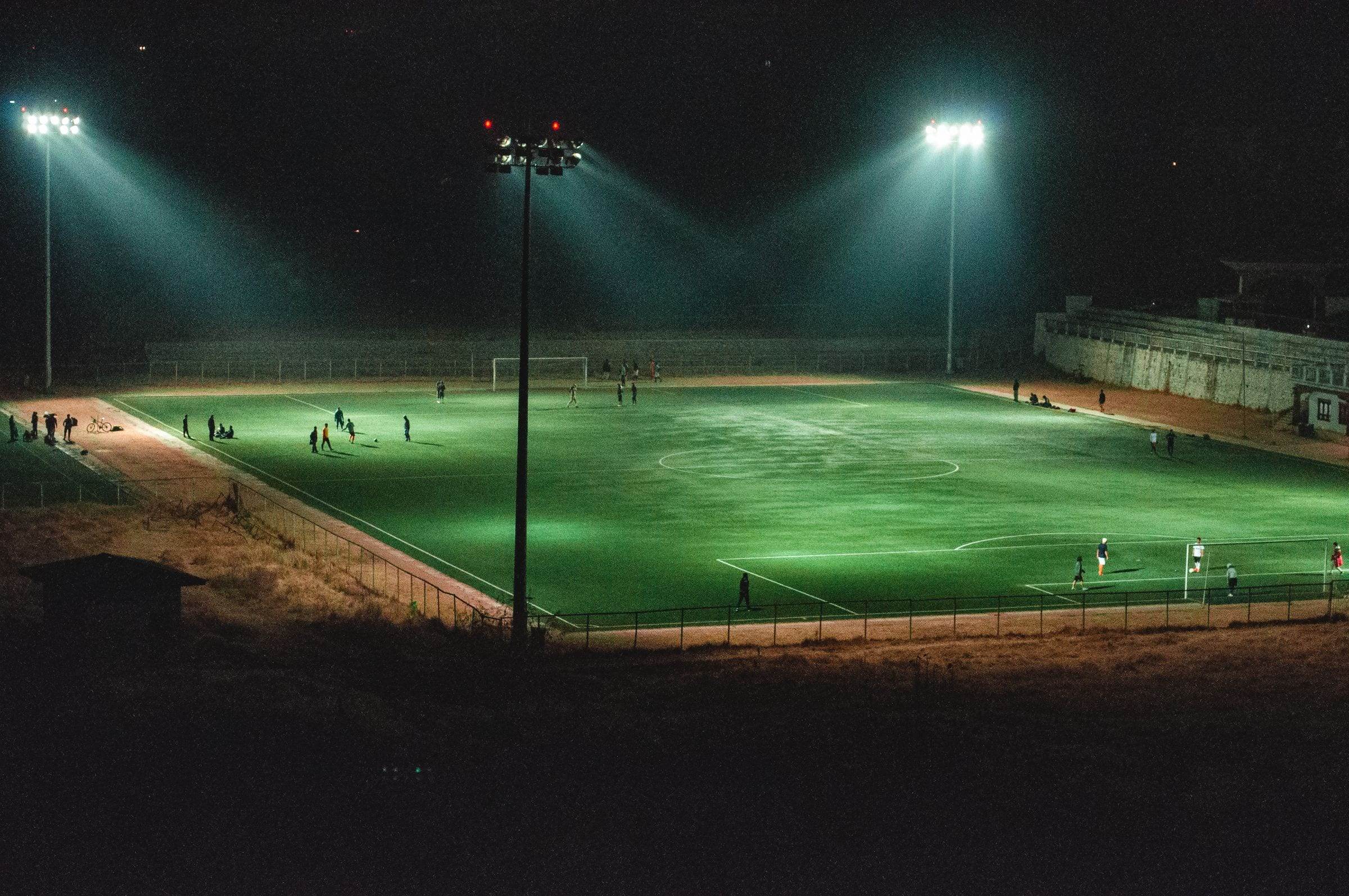 Terrain de football éclairé par des projecteurs, de nuit, vu depuis les hauteurs