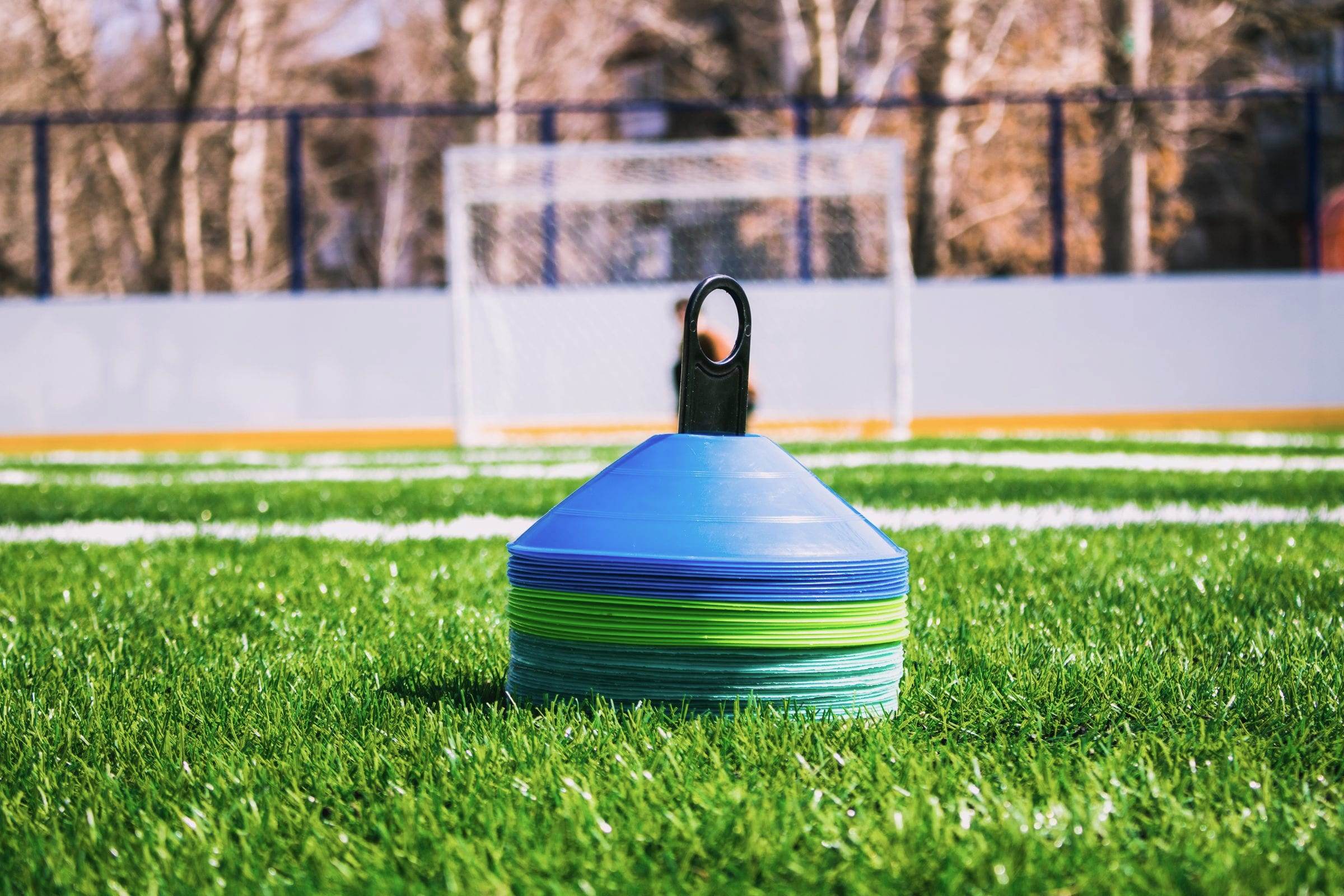 Pile de coupelles d’entraînement posée sur une pelouse, but en arrière-plan
